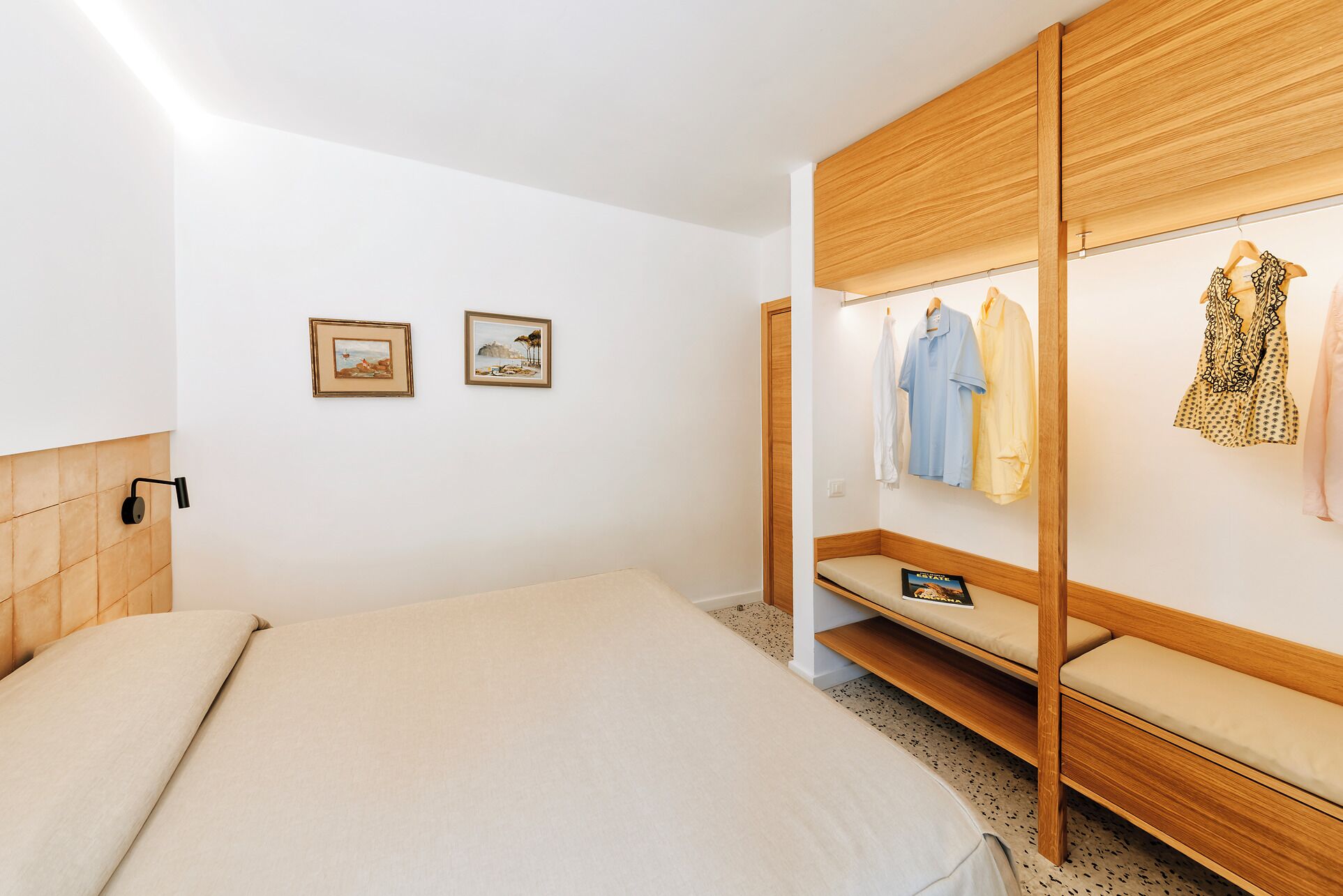 Une chambre à coucher avec un lit, une armoire en bois et deux tableaux encadrés accrochés au mur.