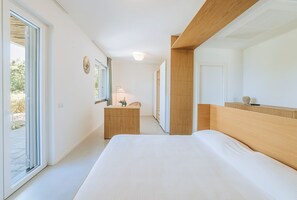 Ein modernes Schlafzimmer mit einem großen Bett, einem Holzkopfstück, einer Kommode und einem Spiegel.