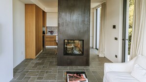 A modern living room with a fireplace, a white sofa, and a magazine on a coffee table.