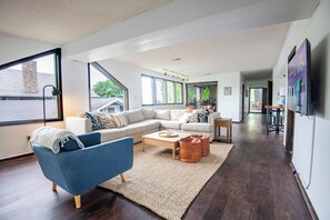 A modern living room with a sectional sofa, a blue armchair, and a coffee table. - Tri-City Split Scene – 2 Units/Groups/Games/Fun (Birmingham)