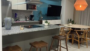 A modern kitchen with a central island, bar stools, a dining table with chairs, and a pendant light. - Spectacular ocean view (Mazatlán)
