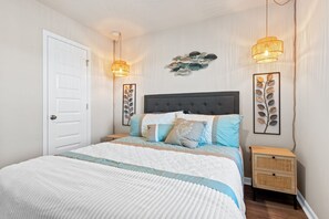A neatly arranged bedroom with a large bed, two bedside lamps, and a small bedside table. - Gorgeous 4-bedroom house with Jacuzzi in Ocean Isle Beach (Ocean Isle Beach)