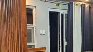 Una habitación con un separador de madera, un letrero de salida de incendios, una puerta y un ventilador.