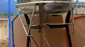 A water tank with a metal structure, connected to a blue pipe and a red valve. - Cozy Escape with WiFi & Smart TV (Dipolog City)