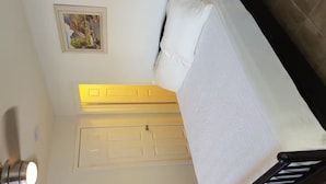 A room with a bed, a white door, a small framed picture on the wall, and a light fixture. - SC Cozy Beach Apartment (San Clemente)