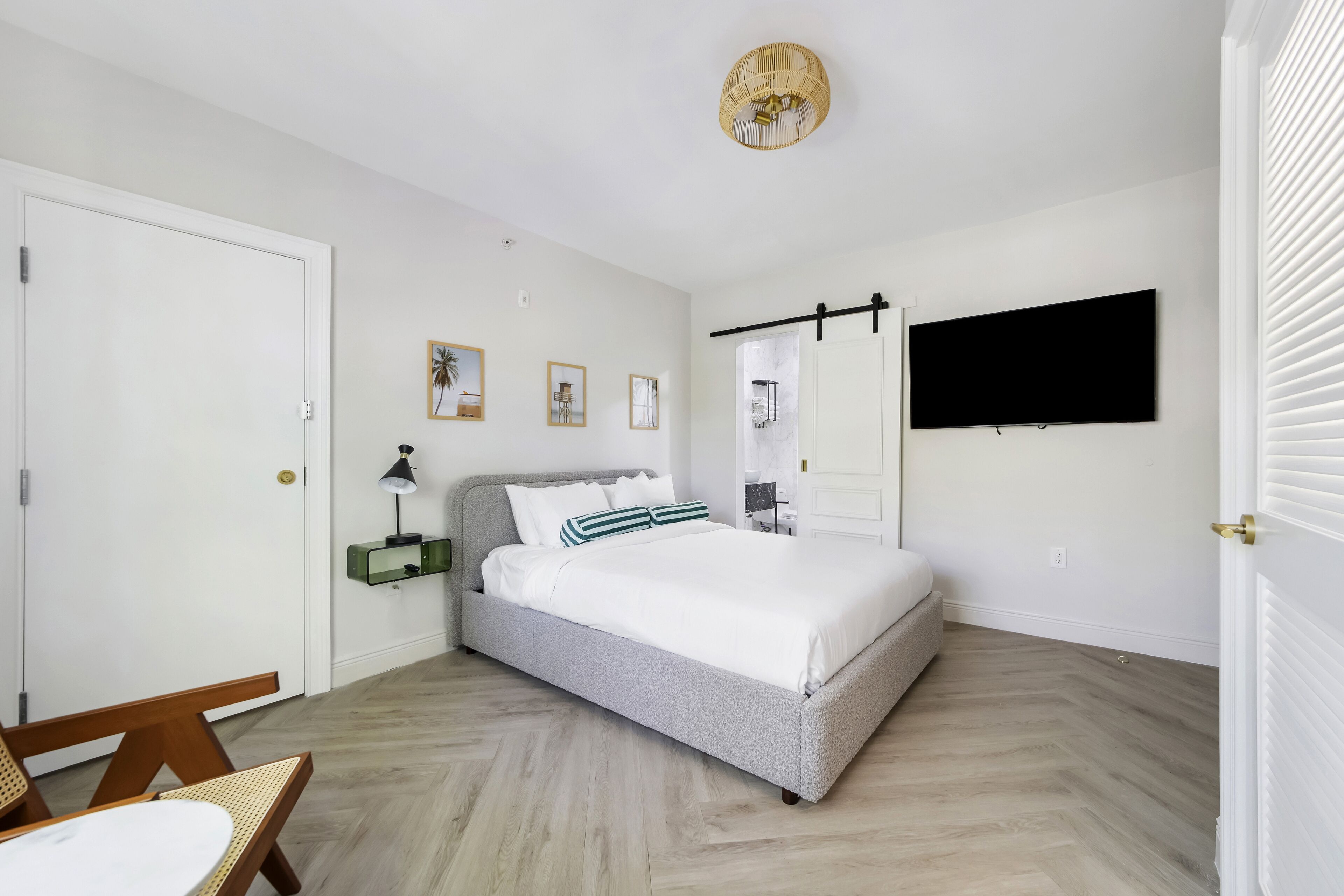 Ein Schlafzimmer mit Bett, Schreibtisch, Stuhl, Fernseher und einer Tür.