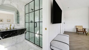 Un bagno moderno con lavabo in marmo, cabina doccia in vetro e una panca.