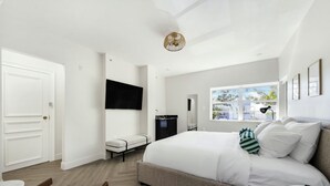 Una camera d'albergo moderna con un letto, una televisione, una finestra con vista e una scrivania.