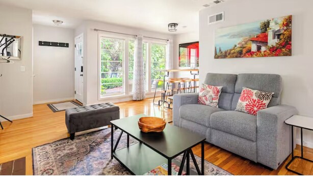 A modern living room with a grey sofa, a coffee table, and a painting on the wall.