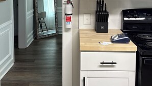 A kitchen with white cabinets, a stove, and a fire extinguisher. - Cozy 2-bedroom bungalow in marvelous Columbus, GA (Columbus)