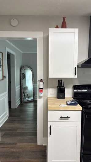 A kitchen with white cabinets, a stove, and a fire extinguisher. - Cozy 2-bedroom bungalow in marvelous Columbus, GA (Columbus)