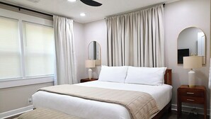 A neatly arranged bedroom with a large bed, two bedside tables, a mirror, and a window with curtains. - Cozy 2-bedroom bungalow in marvelous Columbus, GA (Columbus)