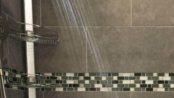 Een douche met een regenkop, een handdouche en een handscrubber.