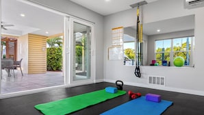 A room with a large sliding glass door leading to an outdoor patio, a ceiling-mounted suspension trainer, and exercise mats. - Hotel Studio (Second Level) - Unit D (Nokomis)