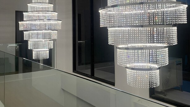 A modern interior with a unique chandelier design, a glass railing, and a window with a view.