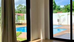 A room with a large sliding glass door leading to an outdoor swimming pool area.