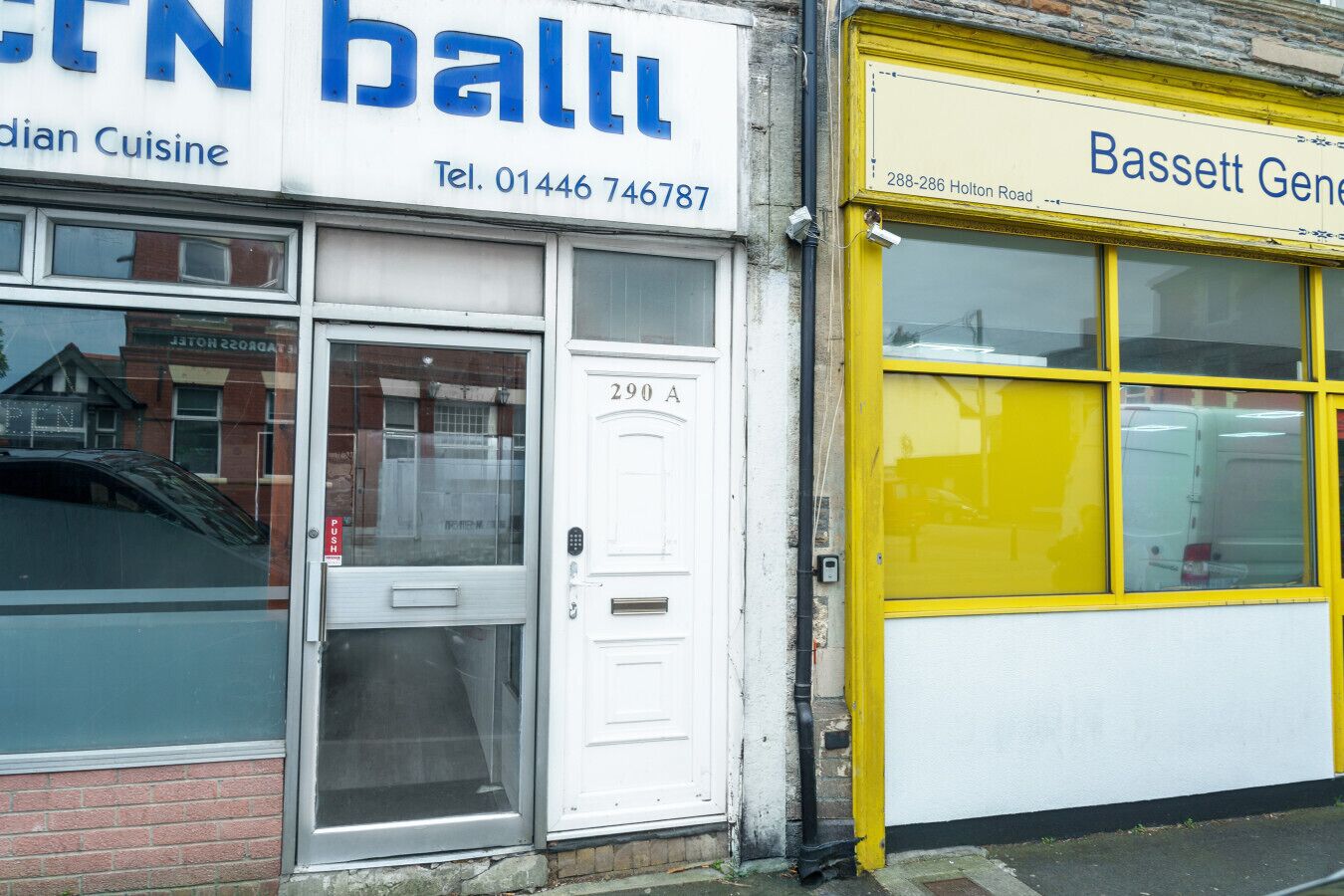 Un edificio con una puerta blanca que indica '290 A' y una puerta amarilla con la señalización '288-286 Holton Road'.