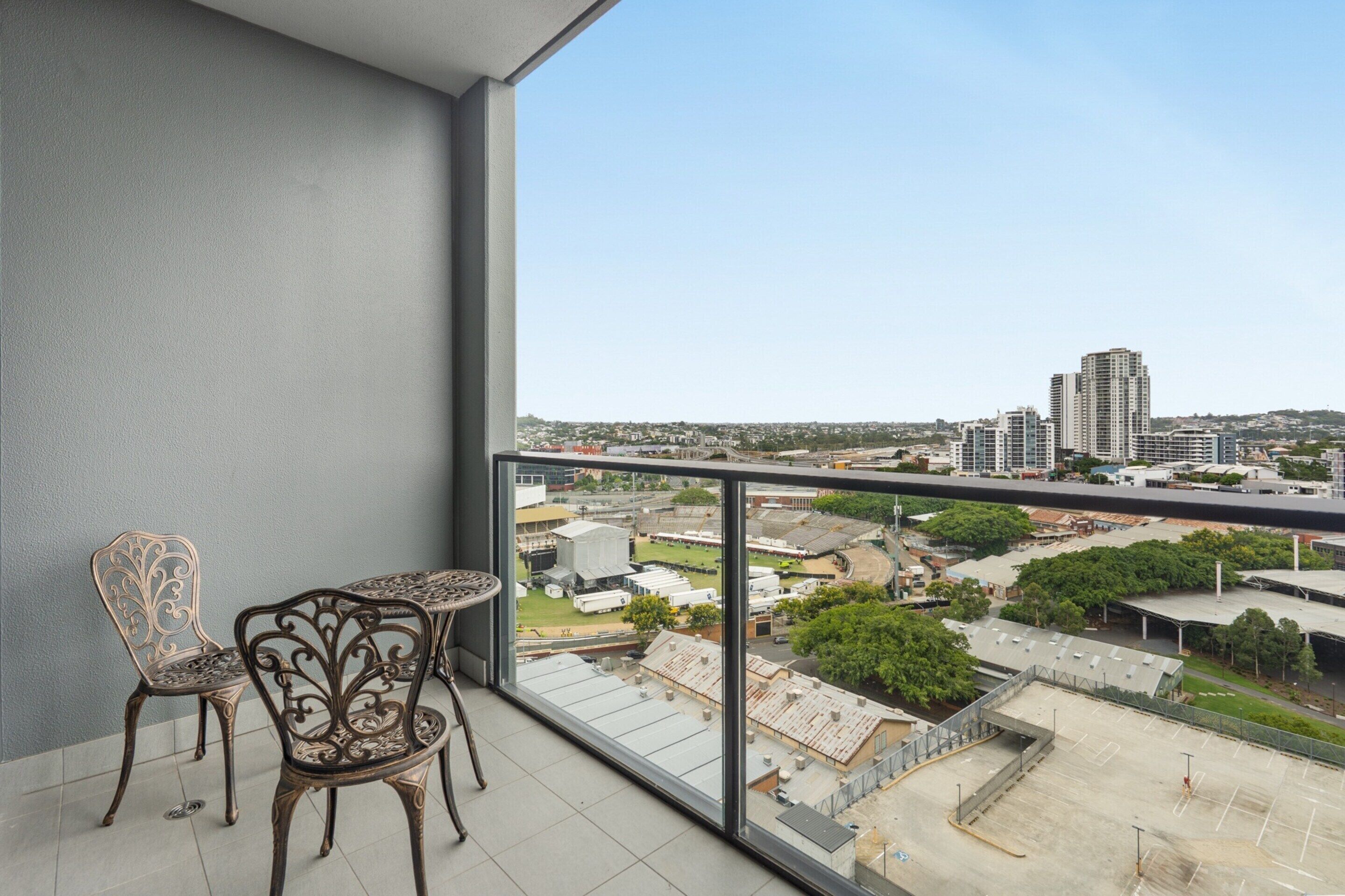 Un balcon donnant sur un paysage urbain, avec une table et deux chaises.