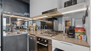 Una cocina moderna con electrodomésticos de acero inoxidable, horno empotrado y cafetera.