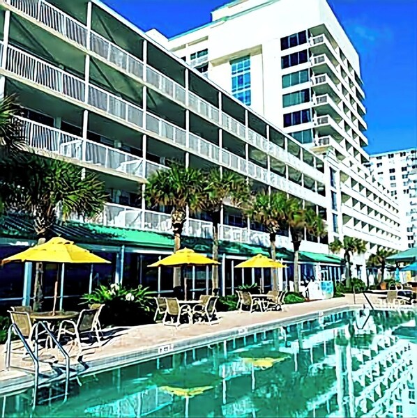 Un hôtel doté d’une piscine, de plusieurs balcons et d’un espace extérieur aménagé avec des parasols.