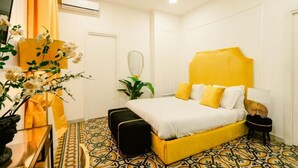 A bedroom with a yellow bed, white pillows, and a patterned floor. - Random Superior  By Dimorra (Naples)