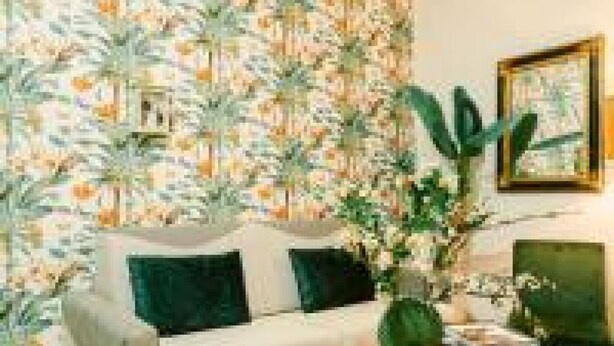 A living room with a patterned wallpaper, a white sofa with green cushions, a coffee table, and a potted plant. - Random Superior  By Dimorra (Naples)