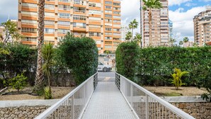 Un sendero conduce a un edificio residencial con un camino adoquinado, rodeado de follaje y palmeras.