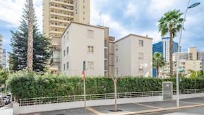 Una zona residencial moderna en la ciudad con edificios de varios pisos, una entrada con puerta de seguridad y cielo despejado.