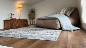 Une chambre à coucher avec un lit, une table de chevet, une lampe, une plante et un tapis à motifs.