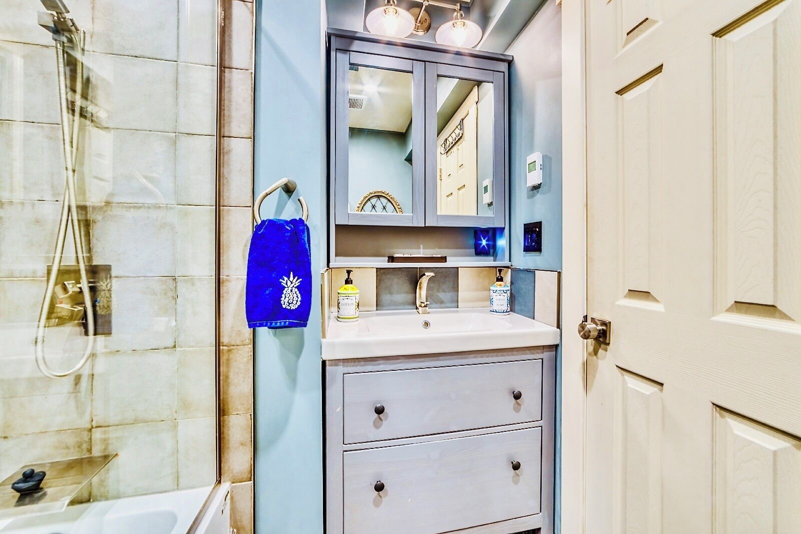 Un baño con ducha, lavabo con espejo y toallero.