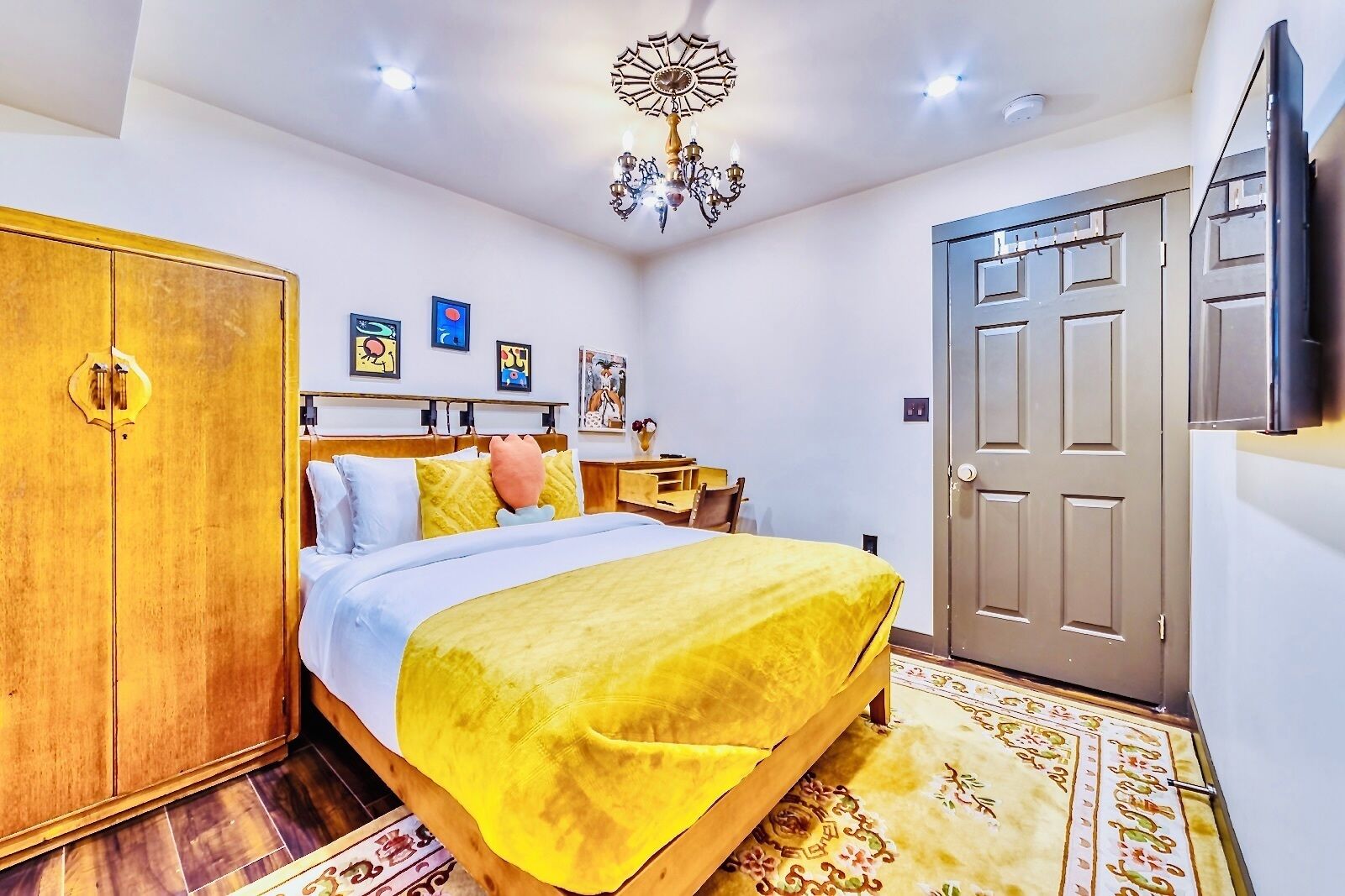 A bedroom with a bed, wardrobe, bedside table, and a door.