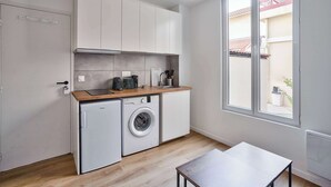 Een kleine keuken met een wasmachine, een spoelbak en een raam met uitzicht op buiten.