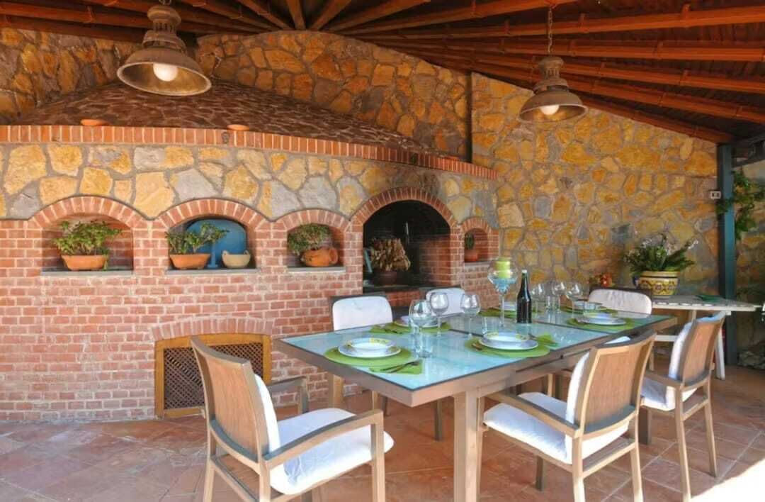 An outdoor patio with a stone wall, a brick fireplace, and a dining table set for four.