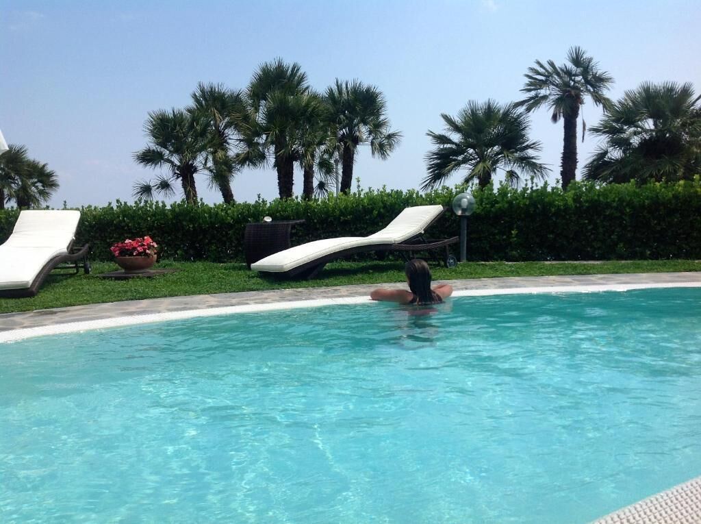 Une piscine avec des chaises longues et des palmiers en arrière-plan.