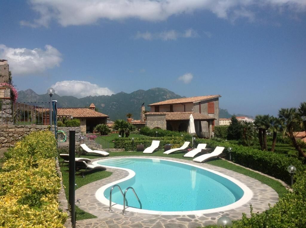 A pool area with lounge chairs, a stone pathway, and a view of mountains in the background.