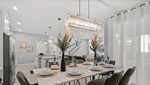 Un espace de salle à manger moderne avec une table en marbre, des chaises en cuir et un lustre.