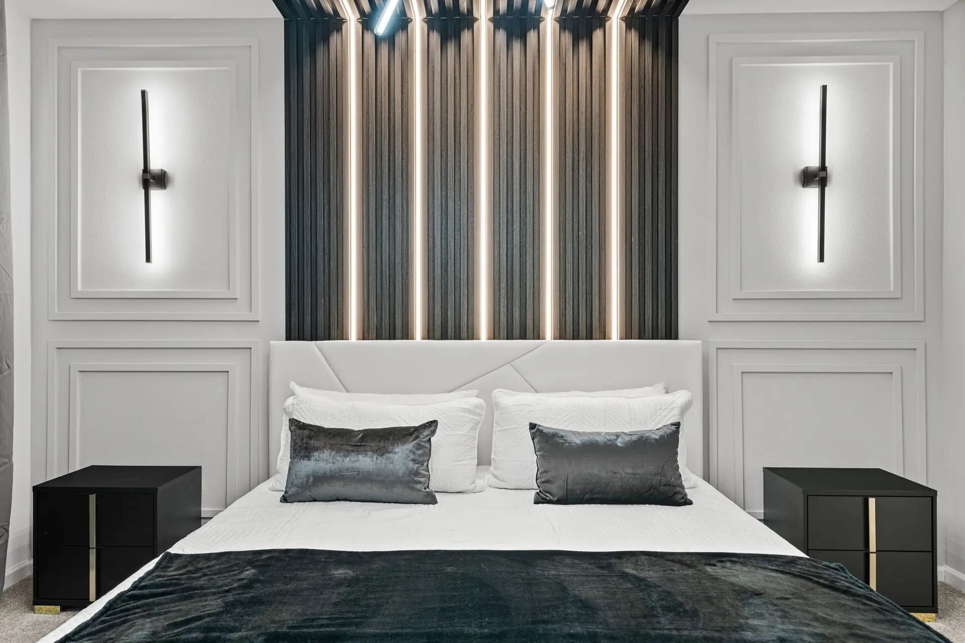 Un dormitorio moderno con una cama grande, dos mesitas de noche y una lámpara decorativa sobre la cama.