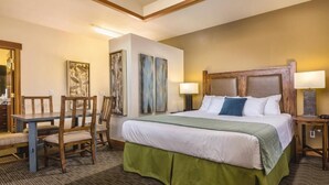Una camera d'albergo con un letto, una scrivania, due sedie e opere d'arte alle pareti.