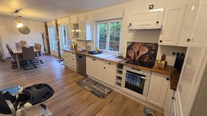 Une cuisine moderne avec des meubles blancs, un plan de travail en bois et un coin repas comprenant une table et des chaises.
