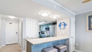 Una cocina moderna con una isla central, dos taburetes de bar y un elemento decorativo en la pared.