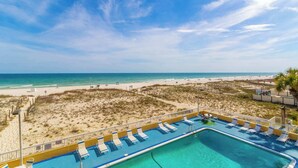 Zona de piscina con sillas de descanso, vista despejada a la playa y un paisaje arenoso.
