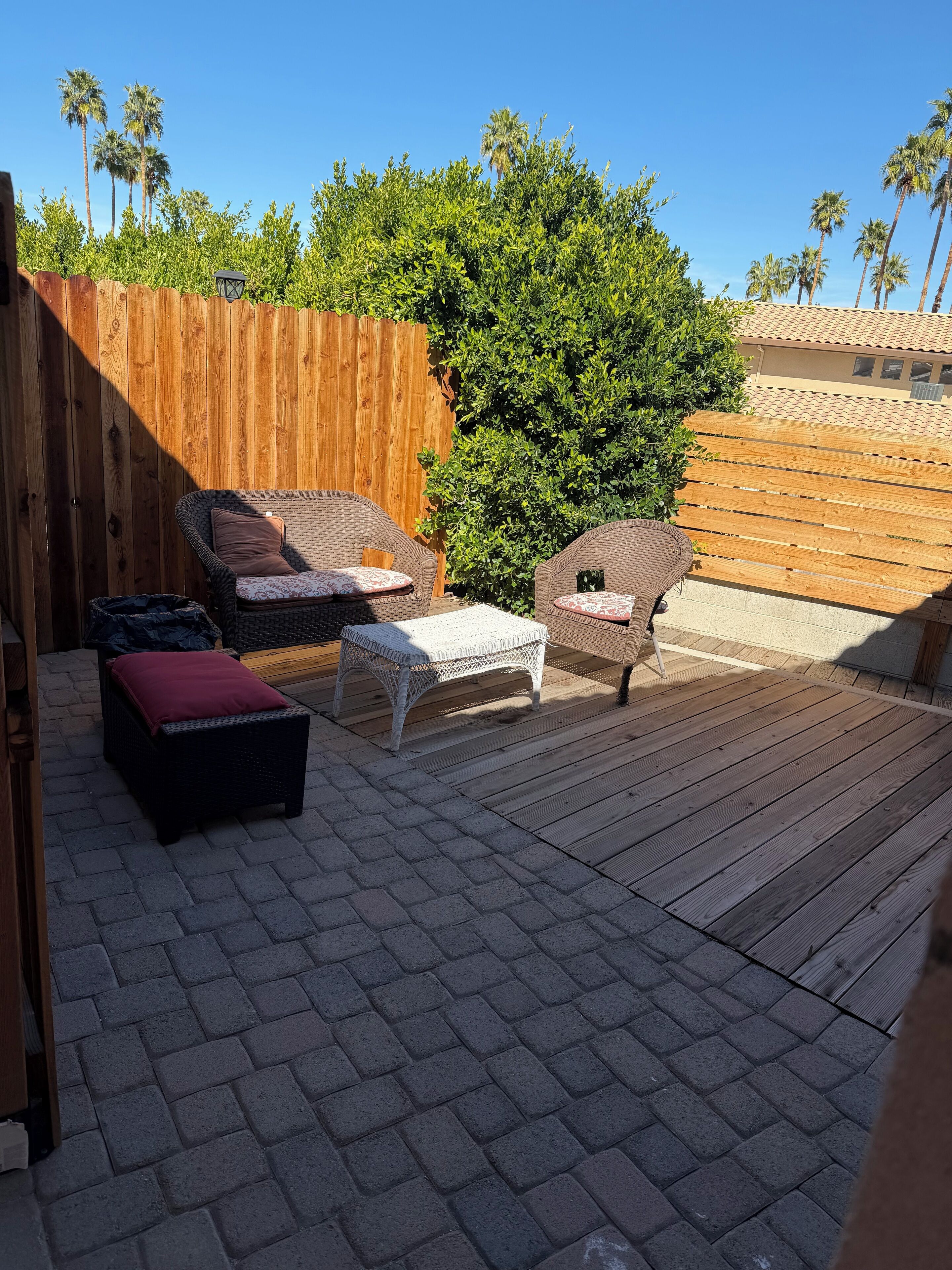 A patio with wicker furniture, a wooden deck, and a wooden fence.