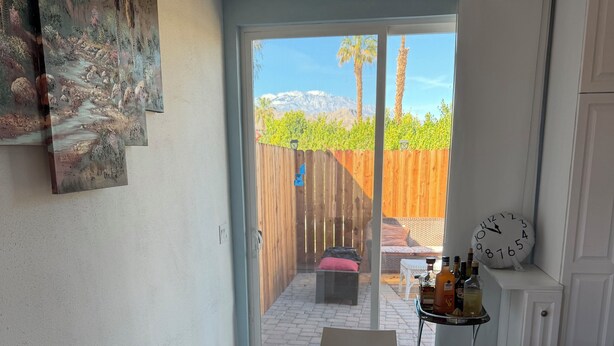 Et lille, godt oplyst rum med et rundt bord, en bænk og en dør til en terrasse.