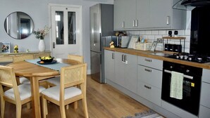 Una cucina moderna con mobili grigi, un frigorifero in acciaio inossidabile, un tavolo da pranzo in legno con sedie e un forno nero.