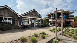 A building with a 'KIDS CLUB' sign, outdoor seating, and a reception area. - VELUWE WELLNESS CHALET - Private Hot Tub and Sauna on Park with Swimming Pool (Voorthuizen)
