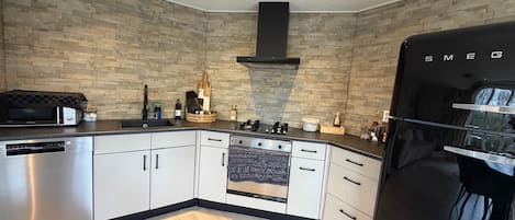 A modern kitchen with a stone backsplash, a black refrigerator, and a built-in oven.