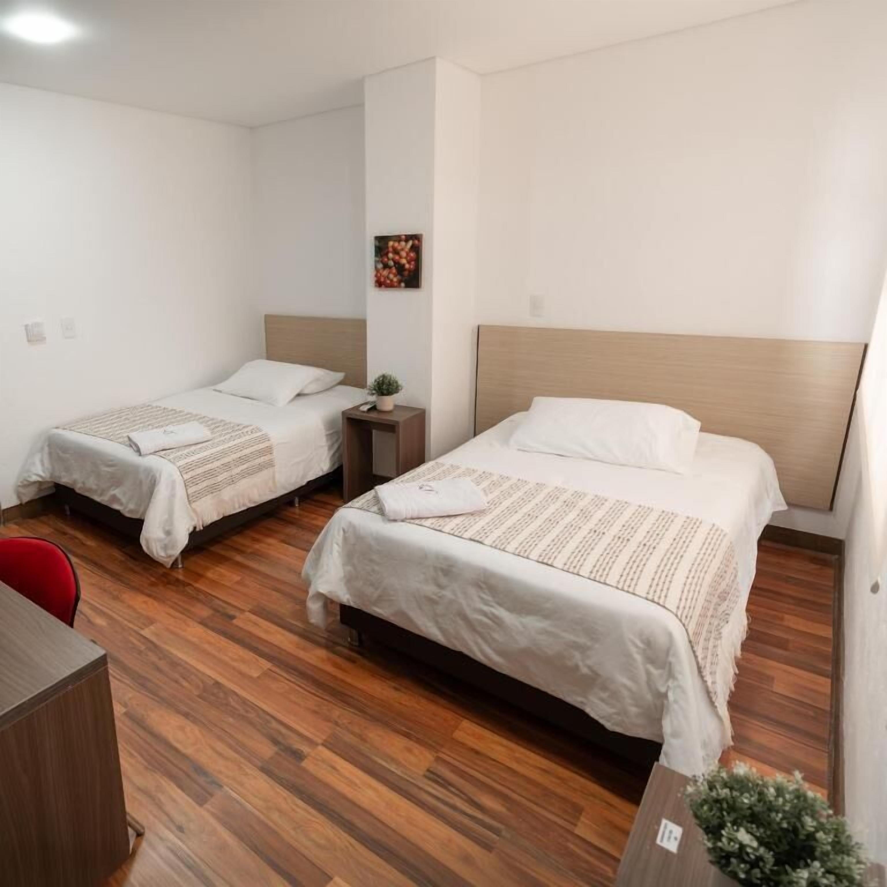 Una habitación de hotel con dos camas individuales, un escritorio pequeño y una silla.