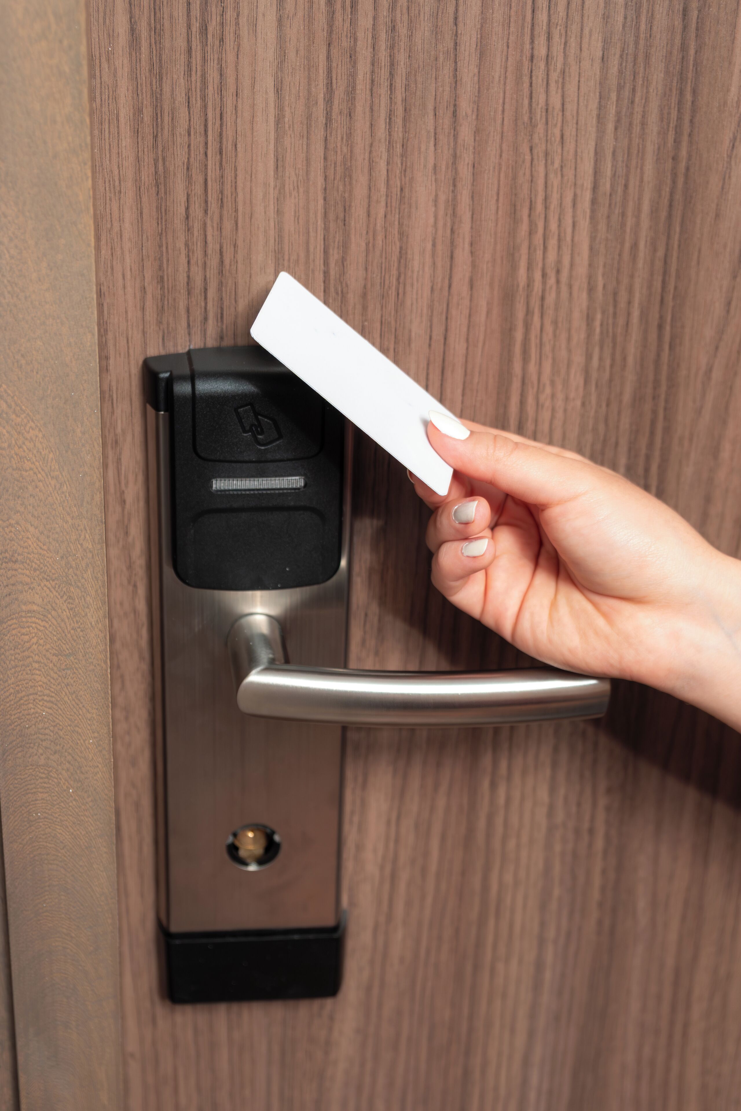 Une main insérant une carte dans le mécanisme de verrouillage d’une porte.