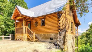 Eine Blockhütte mit einem Metalldach, einer Holztreppe und einem Steinfundament.