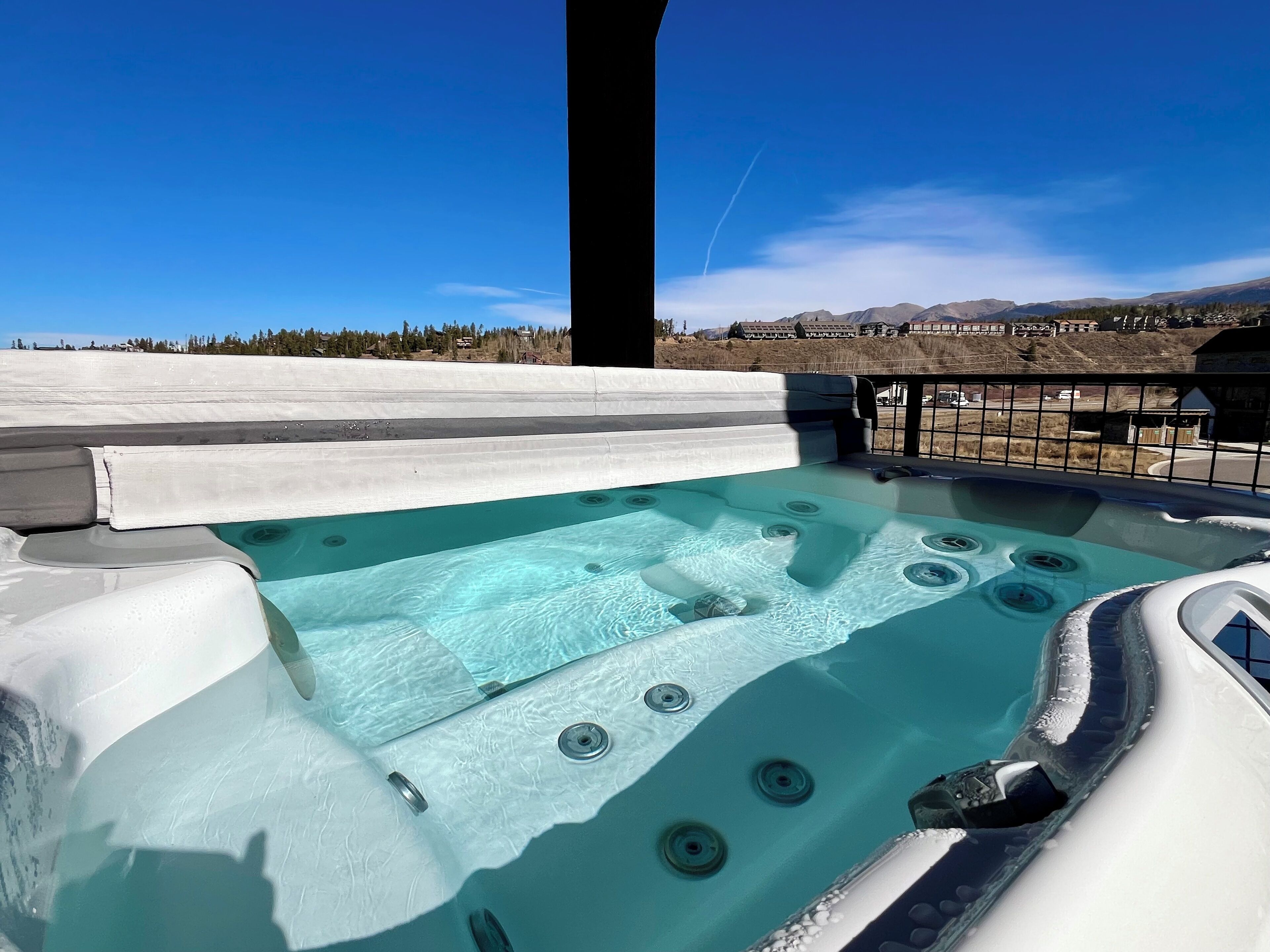 Ein Whirlpool mit freiem Blick auf die umliegende Landschaft, darunter Berge und ein klarer Himmel.